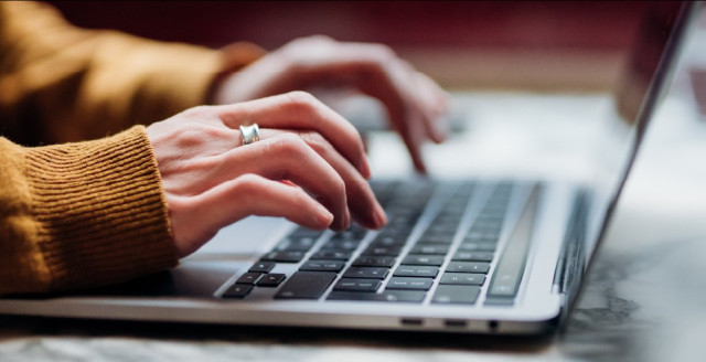 Person types on a laptop keyboard