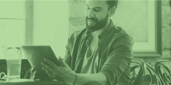 A man with a beer works on a tablet